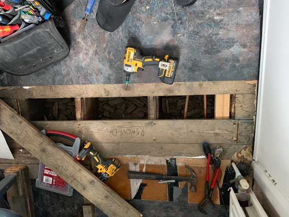 Emergency Plumber Lifting Floorboards To Trace A Leak