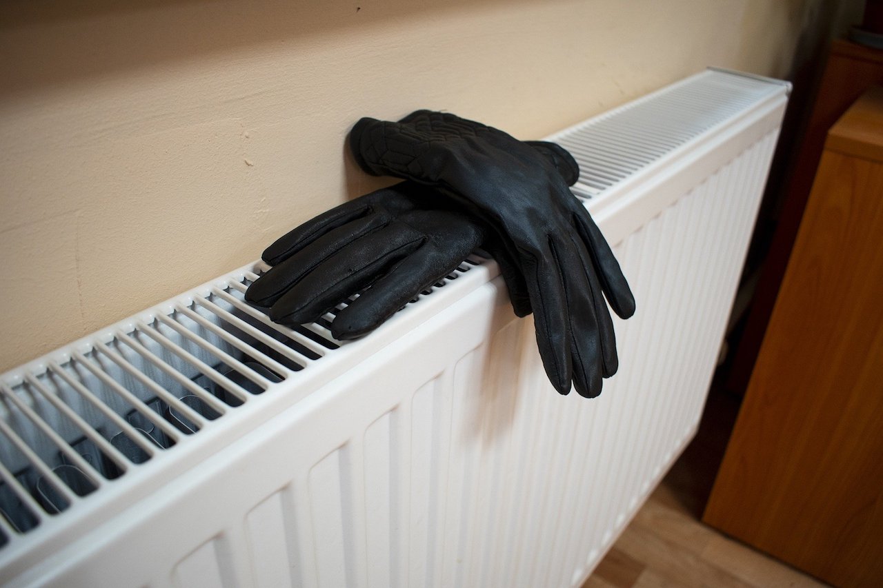 Photo showing a single panel radiator with a pair of black gloves on it.